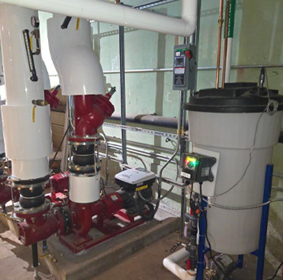 Mechanical room featuring a red commercial pump assembly connected to large white insulated pipes.